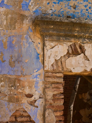 Crumbling parging revealing very old clay brickwork